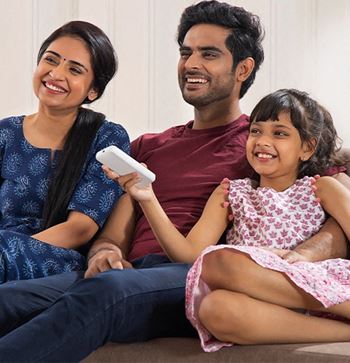 a family sitting on a couch with a little girl holding a remote control